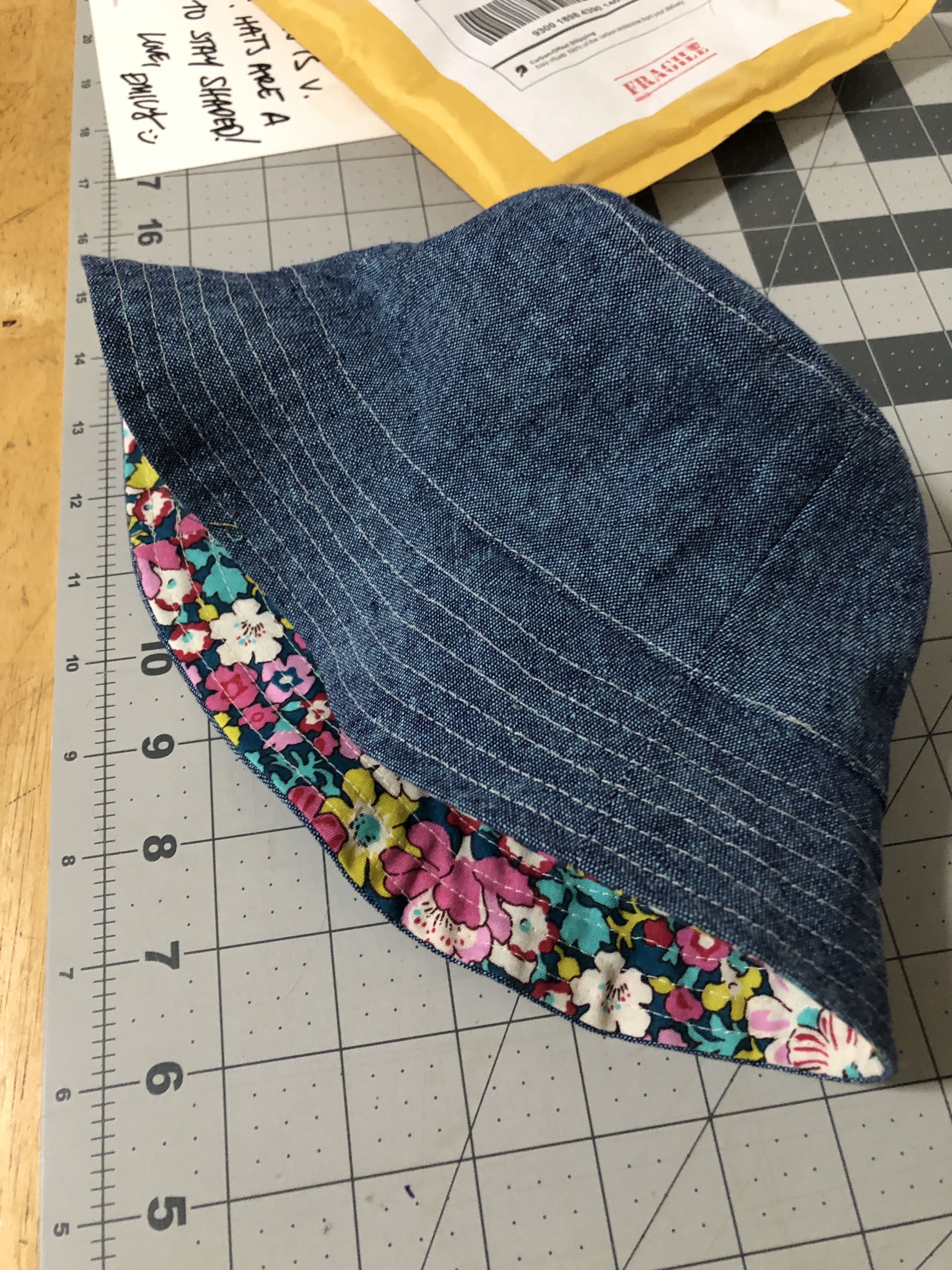 a blue linen/chambray baby-sized bucket hat. Liberty-print lining peeks out.
