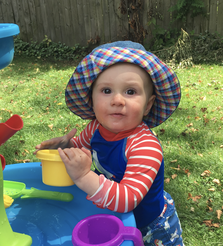 a baby poses for a photo wearing a plaid-lined bucket hat.