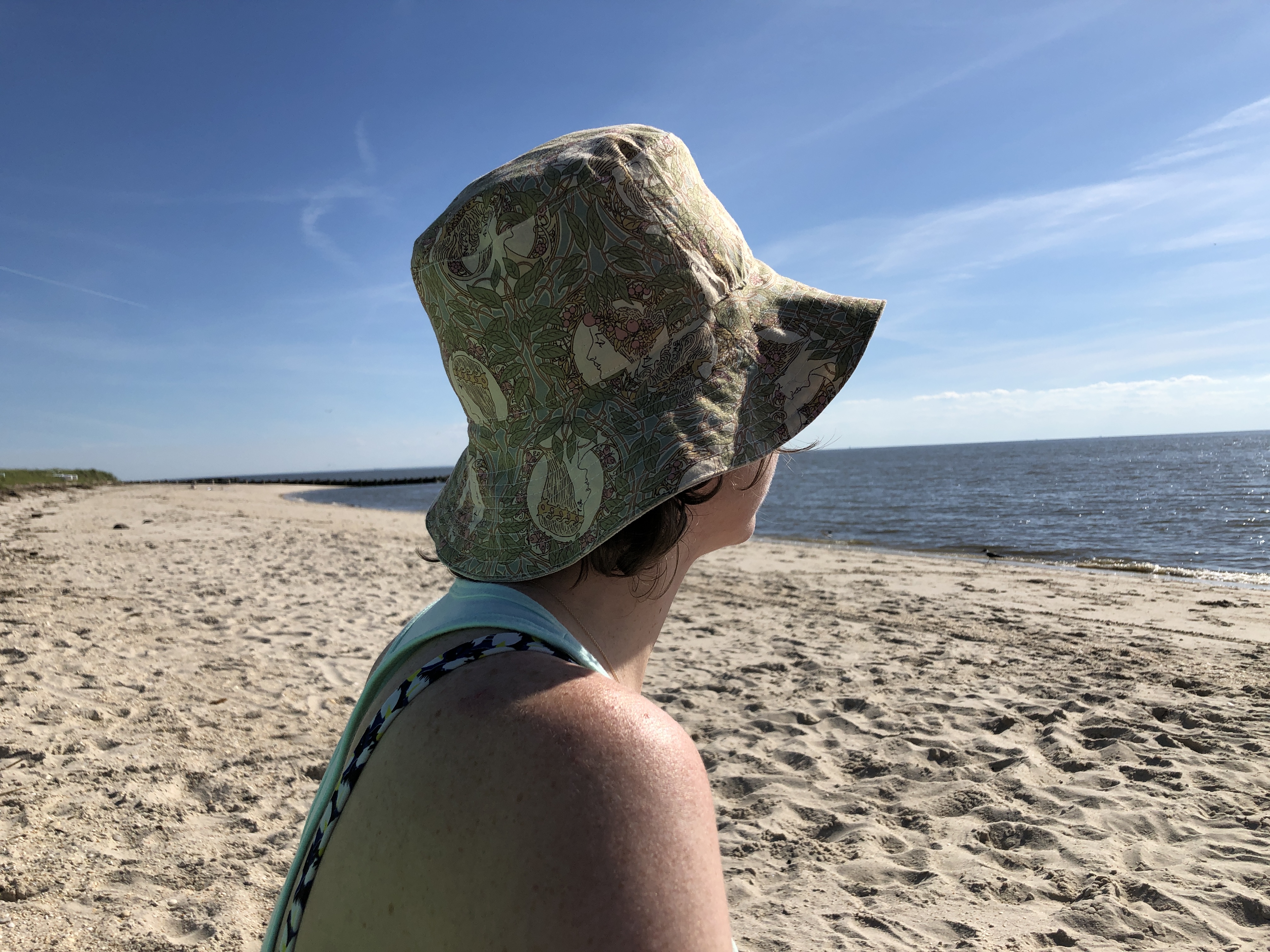 a woman at the beach wearing a patterned bucket hat.