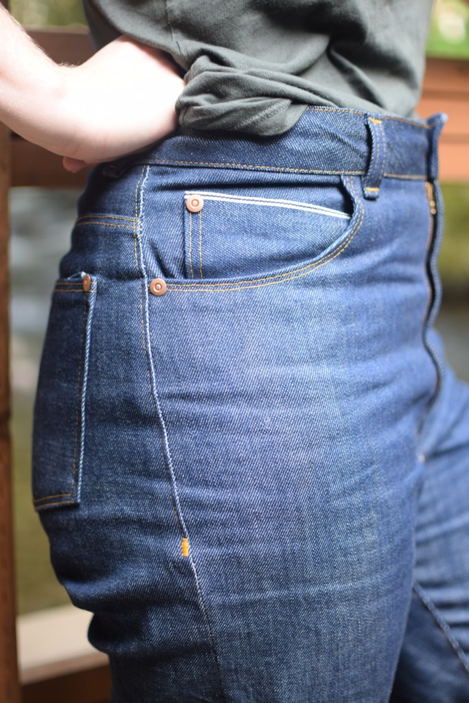 closeup of the rivets and selvedge coin pocket high-waisted, rigid denim Dawn jeans.