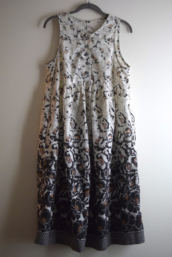 a handmade black and white floral dress on a hanger.