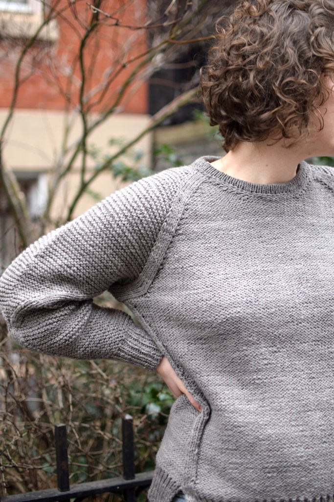 closeup view of a woman wearing a gray sweater she knit.