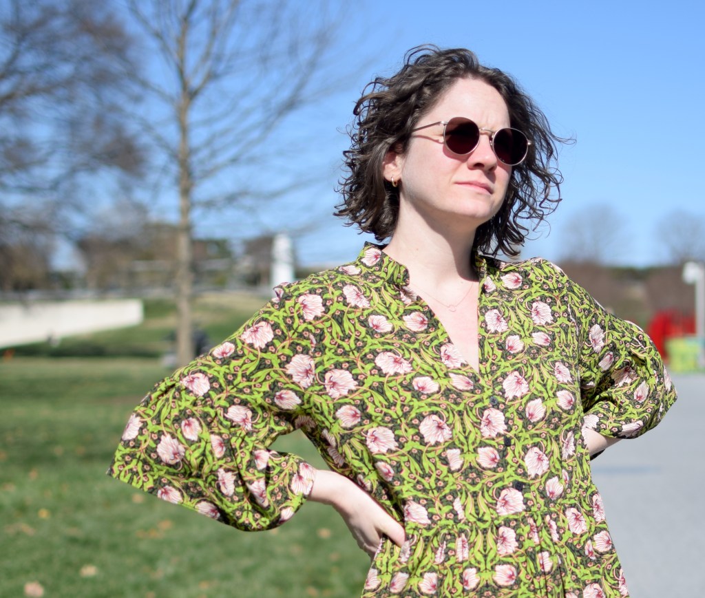 a girl wearing a green and pink floral dress in the bright sun.