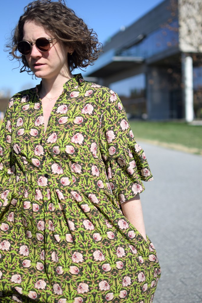 a girl wearing a green and pink floral dress in the bright sun.