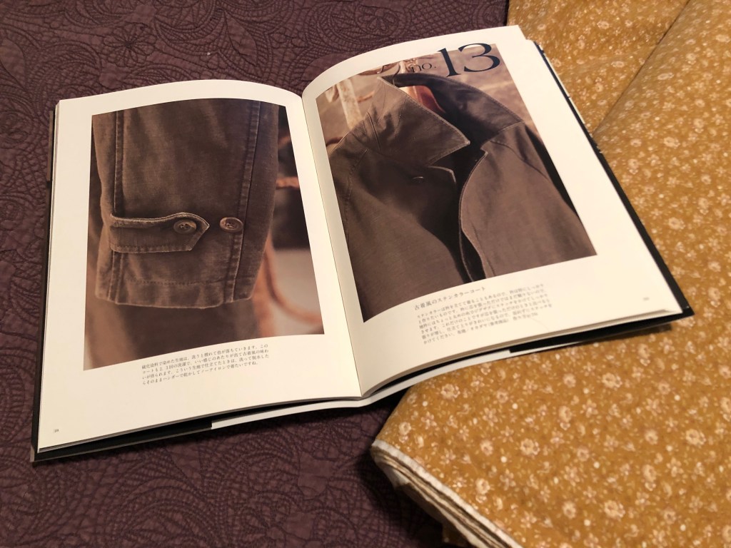 a photo of a sewing book of mens' coat sewing patterns next to a bolt of yellow calico fabric