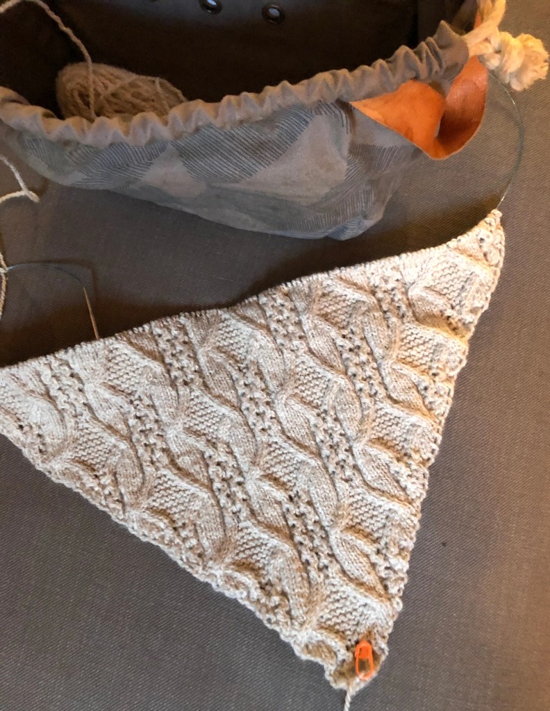 an in-progress photo of a hand knitted light gray shawl