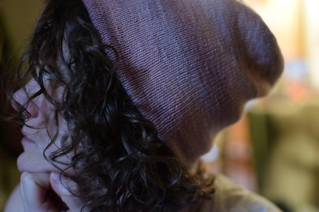 a side view of a hand-knitted pink hat.