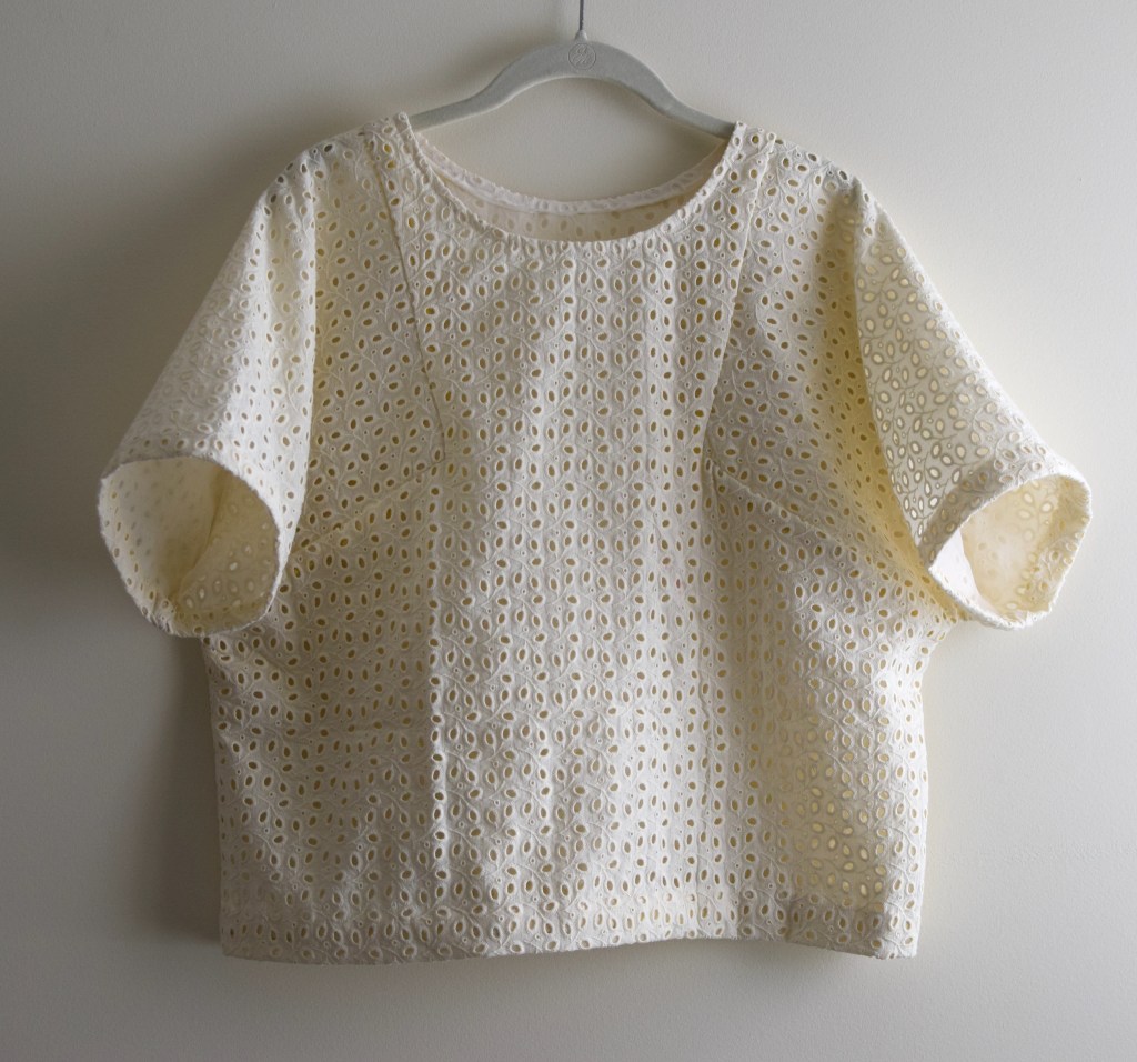 a white eyelet top on a hanger.
