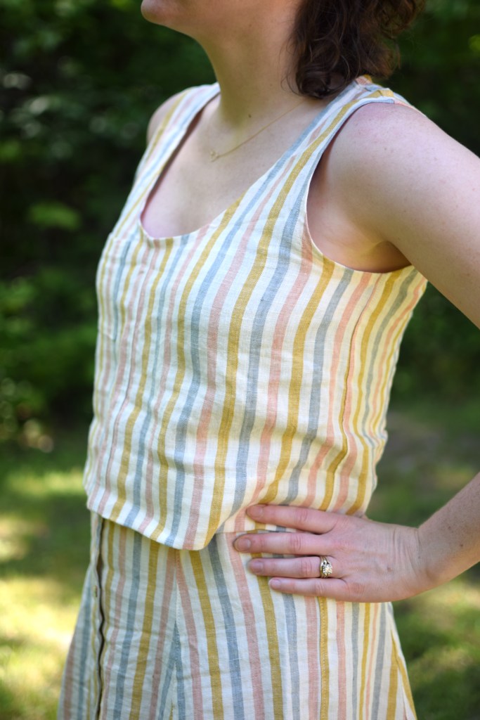 a woman stands outside, wearing a striped Wiksten tank.
