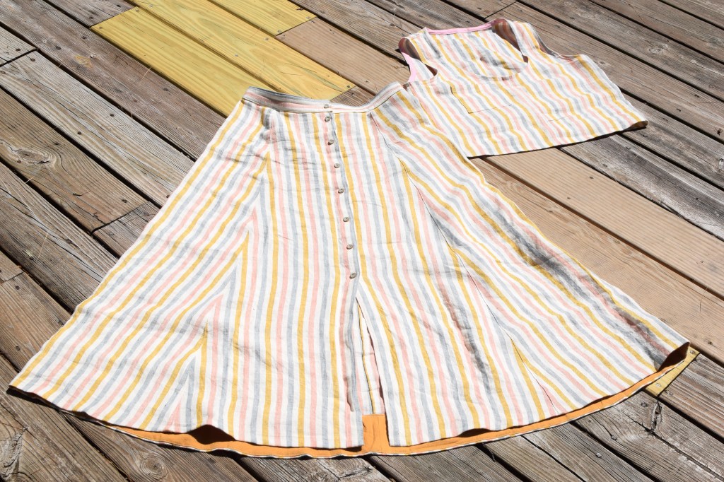A Wiksten tank top and Fumeterre skirt from Deer and Doe laid on a deck.